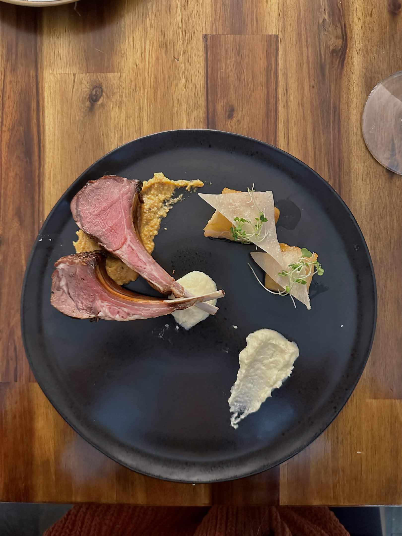 Lamb chops resting on romanesco sauce and parsnip purée on the left, miso black cod garnished with lightly fried wonton triangles and pea sprouts on the right