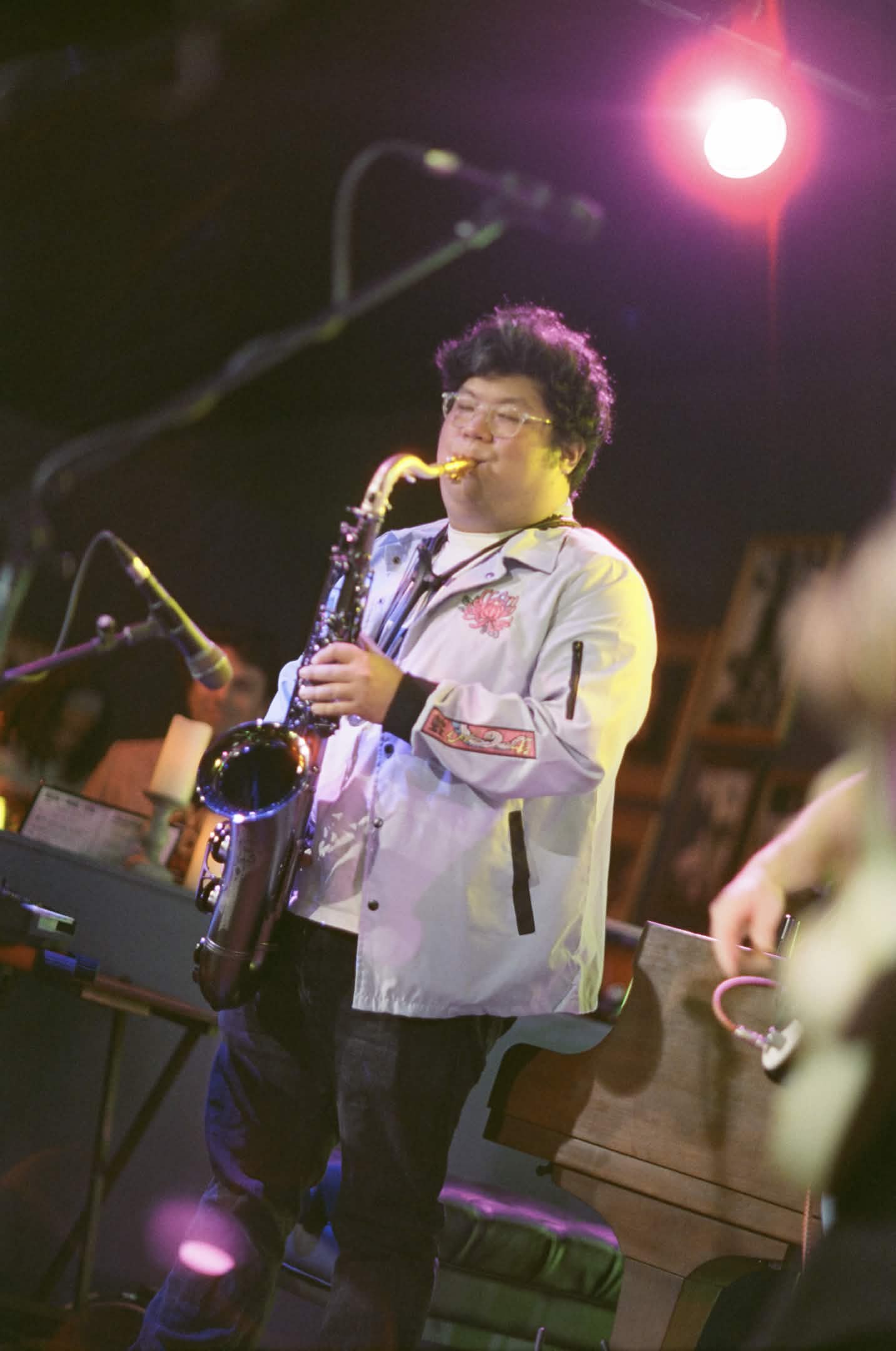 Playing saxophone into a microphone in lavendar jacket