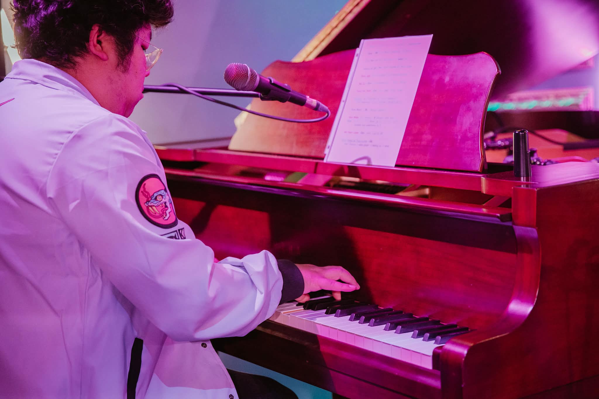 Playing on a grand piano, wearing a lavendar jacket